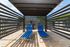 Contemporary outdoor patio with two sleek blue loungers under a stylish pergola, perfect for relaxing on a sunny day.