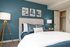 Inviting bedroom with teal accent wall, stylish decor, and cozy bedding, perfect for relaxation and comfort.