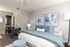 Cozy modern bedroom with stylish decor, featuring a plush bed, abstract art, and a cozy seating area perfect for relaxation.