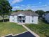 Charming two-story apartment building surrounded by lush green lawns and trees, offering a tranquil residential setting.
