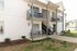 Charming apartment exterior featuring private balconies and cozy patios with modern seating, surrounded by well-maintained greenery and a peaceful neighborhood setting.