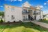 Charming two-story brick apartment building with balconies and lush landscaping under a bright blue sky.