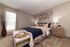 Cozy and elegant bedroom featuring a plush bed with stylish bedding, warm lighting, and modern decor accents.