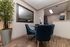 Elegant dining area with sleek glass table, plush blue chairs, modern decor, large mirror, and a view into a stylish kitchen.