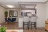 Modern apartment interior featuring a sleek kitchen with granite countertops, stylish breakfast bar with chairs, and cozy dining area with blue velvet chairs and a decorative mirror.