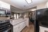 Bright, modern kitchen featuring sleek countertops, stainless steel appliances, and bar seating with view into the cozy living area and elegant dining space.