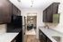 Sleek modern kitchen with elegant dark wood cabinets, stainless steel appliances, and a view into a stylish dining area with plush blue chairs.