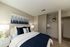 Cozy bedroom featuring a plush bed with navy blue accents, stylish abstract artwork, and an organized open closet.