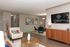 Chic living room with elegant decor at Copper Pointe Apartment Homes, featuring a cozy armchair, modern glass dining table, and sleek wooden floor, perfect for stylish living.