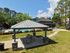 Inviting outdoor area with a cozy gazebo next to a sparkling pool, surrounded by lush greenery and modern seating, perfect for relaxation.