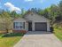 Charming single-story home with attached garage, nestled in a lush, green setting with a welcoming front yard.