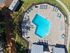 Inviting aerial view of a uniquely shaped swimming pool surrounded by stylish sun loungers and bright green lawns, perfect for relaxation and leisure.