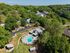 Scenic aerial view of a tranquil residential community surrounded by lush greenery with a central sparkling swimming pool, offering a serene and inviting atmosphere.