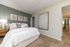 Inviting bedroom with plush carpeting, modern art, and stylish wooden nightstand, perfect for relaxation.