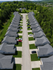 Charming aerial view of a suburban neighborhood with rows of identical houses lining a well-maintained street, surrounded by lush greenery and beautiful landscape.