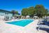 Inviting outdoor pool area with stylish lounge chairs, surrounded by lush trees and modern apartment building.