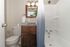 Elegant bathroom featuring a sleek vanity with a granite countertop, modern lighting, and a stylish shower curtain enhancing a crisp, clean atmosphere.