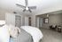 Spacious bedroom featuring modern ceiling fans, plush carpeting, and cozy seating area, perfect for relaxation.