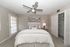 Bright and inviting bedroom with a modern ceiling fan, plush bedding, and a chic closet space.