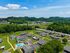 Scenic aerial view of a modern apartment community with lush green surroundings, featuring stylish homes, winding pathways, and a central swimming pool.
