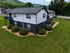 Charming two-story apartment building with stylish black and white exterior, nestled in lush greenery with scenic mountain views.
