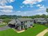 Charming apartment complex with lush green lawns, set against serene mountain views under a bright blue sky.