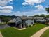 Charming apartment building surrounded by lush green lawns and a clear blue sky, offering serene suburban living.
