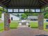 Charming outdoor view featuring a covered pavilion with stone pillars, stylish outdoor grill, and vibrant communal area with lush greenery.