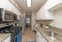 Modern kitchen with sleek stainless steel appliances, elegant granite countertops, and stylish white cabinetry leading to a cozy dining area.