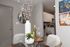 Modern dining area with elegant glass table, chic white vase, and artistic wall decor, adjacent to a stylish kitchen.