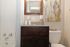 Modern bathroom featuring a sleek vanity with granite countertop, elegant mirror, and contemporary artwork for a stylish touch.