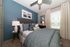 Inviting bedroom with elegant blue accent wall, cozy bedding, and stylish decor.