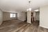 Inviting open-floor apartment showcasing a seamless blend of modern laminate and cozy carpet flooring, with a well-lit kitchen and spacious living area.