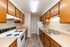 Charming galley kitchen with warm wood cabinets, sleek countertops, and modern appliances for a cozy culinary experience.