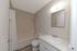 Modern bathroom featuring a sleek vanity with a mirror, bathtub with shower, and elegant lighting.