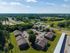 Aerial view of a serene suburban neighborhood with neatly arranged apartment buildings surrounded by lush greenery and open fields.