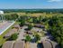 Aerial view of a serene apartment complex surrounded by lush greenery and open fields, with ample parking and a nearby water tower.