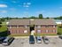 Inviting two-story brick apartment building with ample parking, set against a clear blue sky and lush green surroundings.