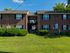 Charming brick apartment complex with lush green landscaping, showcasing a welcoming and serene residential atmosphere.