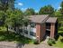Charming two-story apartment building with brick facade, nestled in lush greenery and offering a serene suburban lifestyle.