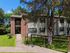 Charming apartment building surrounded by lush greenery and a welcoming pathway, ideal for a cozy and serene lifestyle.