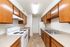 Charming galley-style kitchen with warm wooden cabinetry, modern appliances, and ample countertop space.