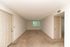 Bright and spacious empty room with neutral tones, plush carpeting, and a large window offering a green view.