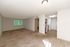 Inviting apartment interior with spacious living room, plush carpet, and bright natural light through large window, adjacent to a modern kitchen.