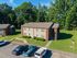 Charming apartment building surrounded by lush greenery, featuring ample parking and a welcoming entrance.