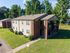 Charming two-story apartment building with brick and siding exterior, nestled in a lush green landscape with ample natural light.
