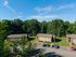 Charming apartment complex nestled in lush greenery with ample parking and vibrant landscaping.