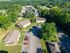Bird's-eye view of a charming apartment community nestled in lush greenery, featuring well-maintained buildings, ample parking, and serene surroundings perfect for a peaceful lifestyle.