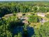 Aerial view of charming apartment complex nestled in lush greenery with ample parking and serene surroundings.