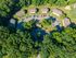 Charming apartment complex surrounded by lush greenery, featuring several buildings with ample parking and a peaceful neighborhood feel.